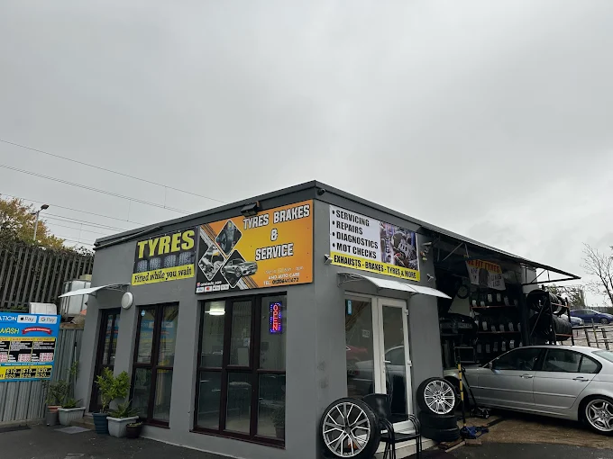 The AMD Tyres, Brakes and Service shopfront on North Station Road, Colchester, with tyres racked outside and a car on the forecourt